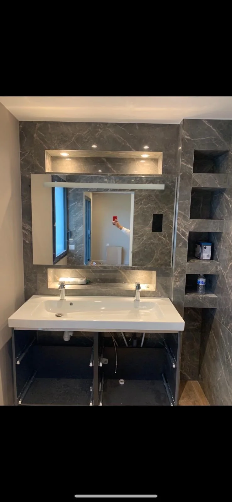 Salle de bains avec habillage effet marbre et niches éclairées